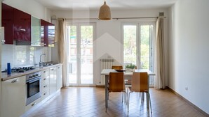 A spacious kitchen with a dining area, large windows, and a hanging light fixture. - Karismatico - Three-room apartment on the first floor a few steps from the sea (Pineto)