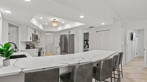 Een moderne keuken met een groot eiland, witte kasten en een dakraam.