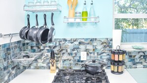 A kitchen with a stove, pots, a spice rack, and a window with a view of trees. - Miami Boho Beach Place - Great location for all your needs! (Hialeah)