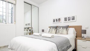 A modern bedroom with a large bed, a nightstand, a bedside table, and a mirror. - Ruiz Gijón Elegant and modern in the most authentic Seville (sevilla)