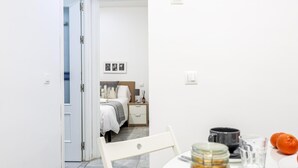 A modern hotel room with a bed, bedside table, and a small table with a glass jar and orange fruit. - Ruiz Gijón Elegant and modern in the most authentic Seville (sevilla)