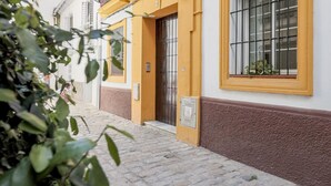 A narrow cobblestone street with a building featuring yellow doors and windows. - Ruiz Gijón Elegant and modern in the most authentic Seville (sevilla)