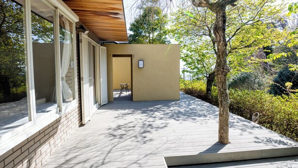 A modern building with large windows, a wooden ceiling, and a paved pathway leading to a table. - vacation inn  Izu Kogen (Ito)