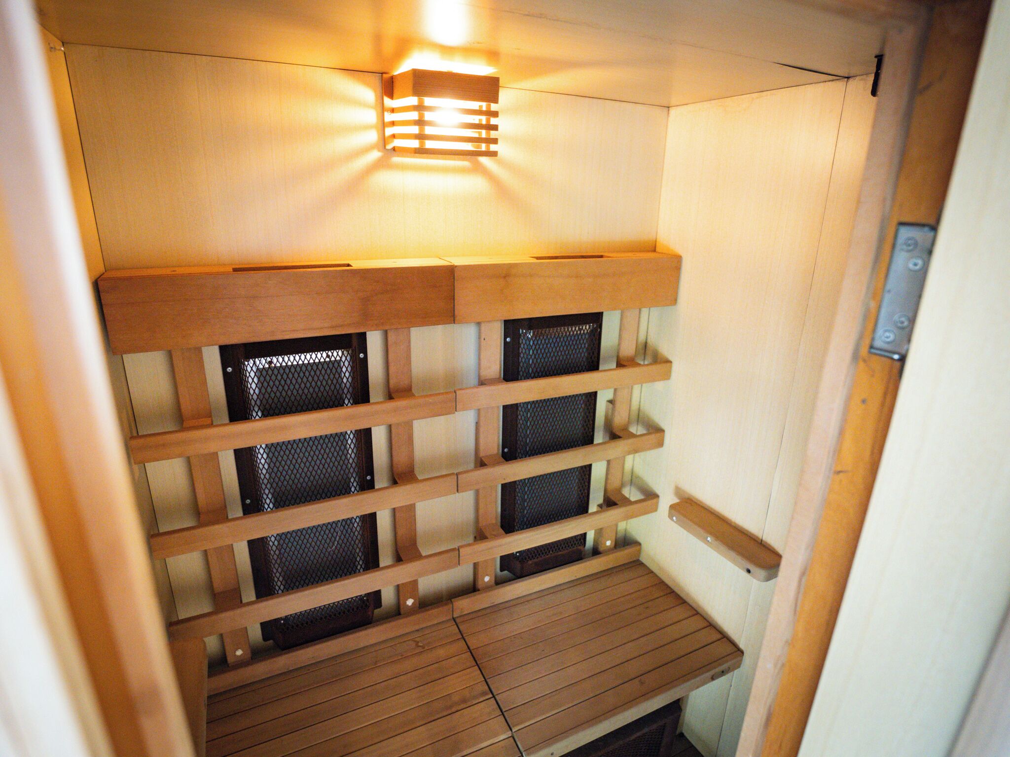 A sauna with wooden benches and a ceiling light.