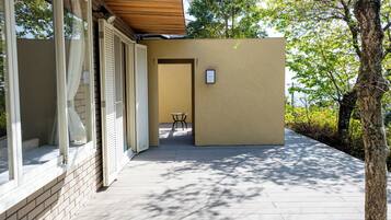 A modern building with a wooden deck, a small table, and a door leading to an interior space.