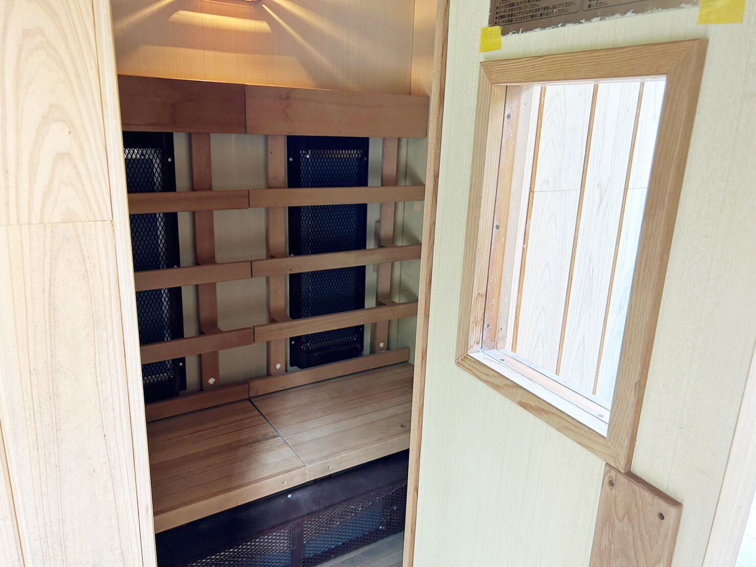 Une pièce de taille modeste, dotée d’un plancher en bois, d’une fenêtre et d’une cloison en treillis métallique.