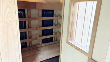 Une pièce de taille modeste, dotée d’un plancher en bois, d’une fenêtre et d’une cloison en treillis métallique.