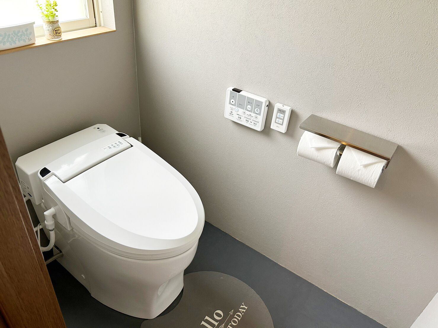 A modern bathroom with a white toilet, a wall-mounted bidet, and a toilet paper holder.