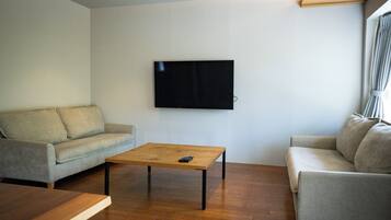 A living room with a sofa, a coffee table, and a TV mounted on the wall.