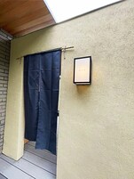 Una puerta con una cortina oscura, un cartel enmarcado en la pared y un techo de madera.