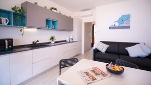 Eine moderne Küche mit weißen Schränken, einer schwarzen Arbeitsplatte und einem Essbereich mit Tisch und Stühlen.