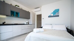 Ein modernes Hotelzimmer mit einem Bett, einer kleinen Küchenzeile und einem Bild an der Wand.