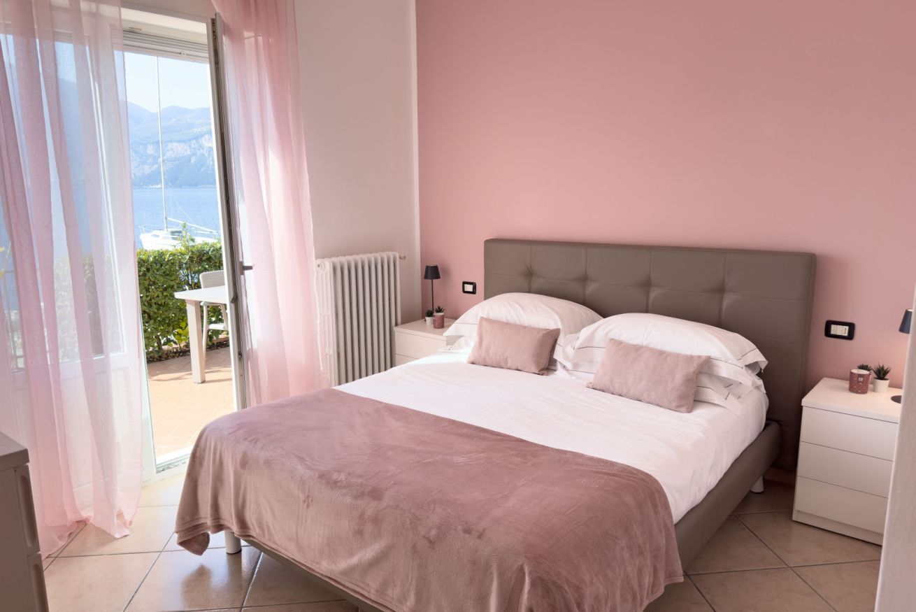 Une chambre à coucher comprenant un lit, une table de chevet, une lampe, une fenêtre avec des rideaux et une vue sur l’extérieur.