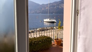 Ein Balkon mit Blick auf einen stillen See, ein Segelboot und ferne Berge.