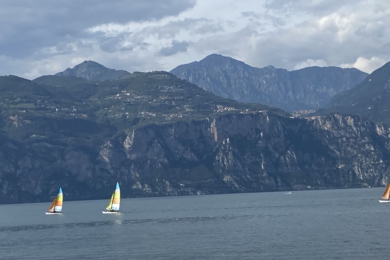 A coastal landscape with sailboats on the water and mountains in the background.
