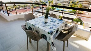 Een balkon met een tafel voor twee, met uitzicht op een stadsbeeld met gebouwen en een waterpartij.