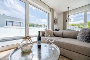 Un soggiorno moderno con un tavolo in vetro, una bottiglia di vino e due bicchieri da vino.