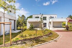 A modern two-story house with a paved driveway and a well-maintained garden.