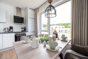 Une cuisine moderne avec un coin repas, de grandes fenêtres et une vue sur un immeuble.