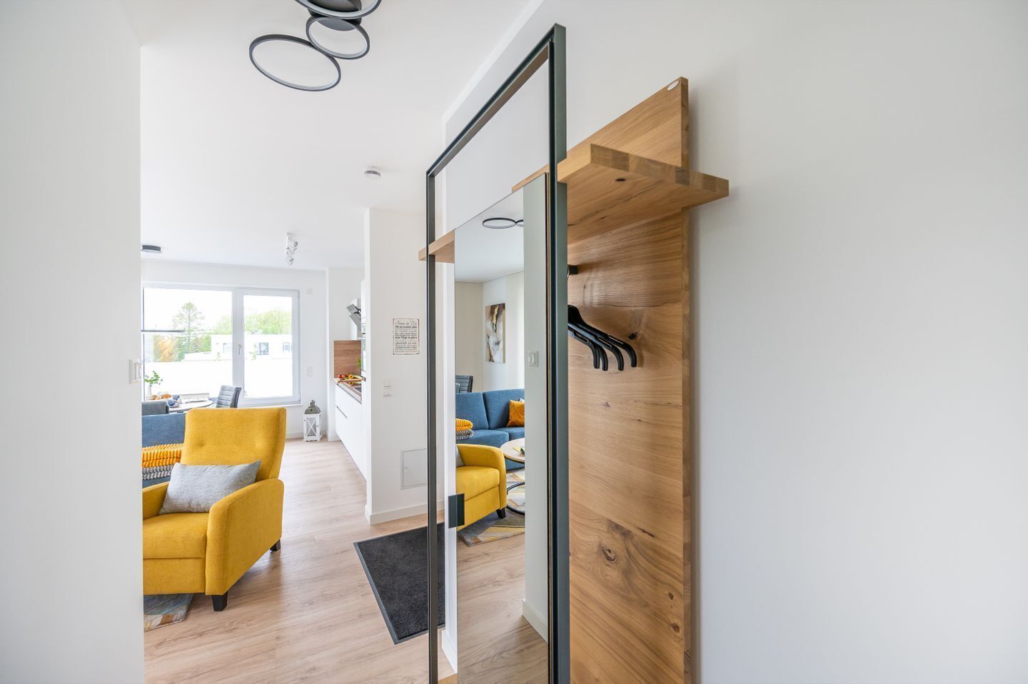 Een modern interieur met een houten wand, een gele fauteuil en een bank.