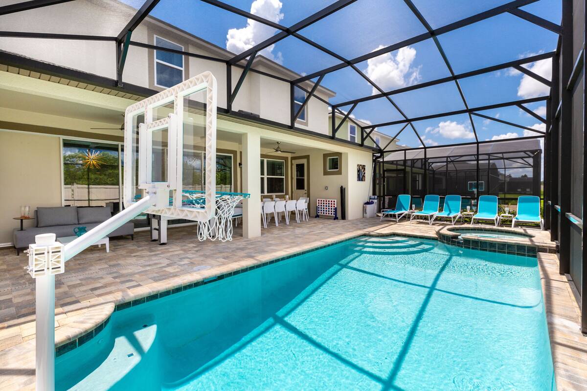 An indoor swimming pool with a glass ceiling, surrounded by lounge chairs and a sunbed.