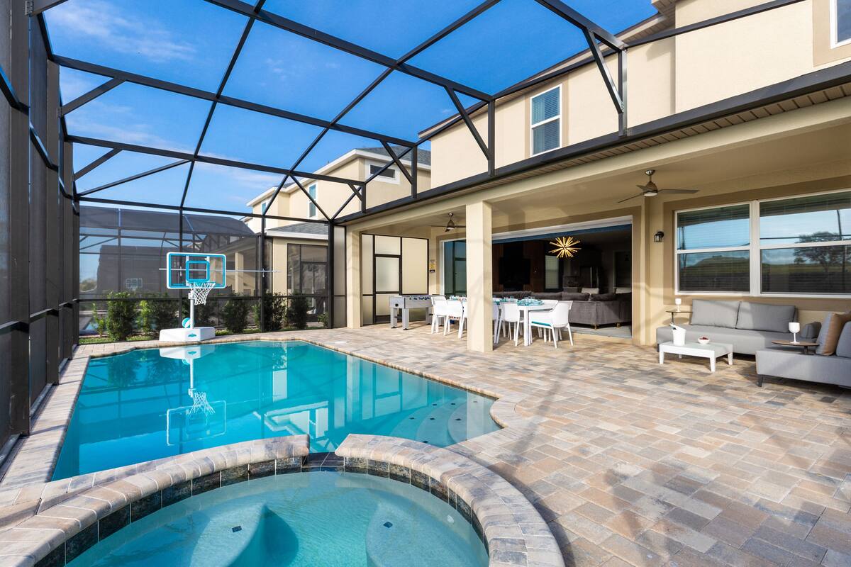A swimming pool with a glass enclosure, outdoor seating area, and a patio with tables and chairs.