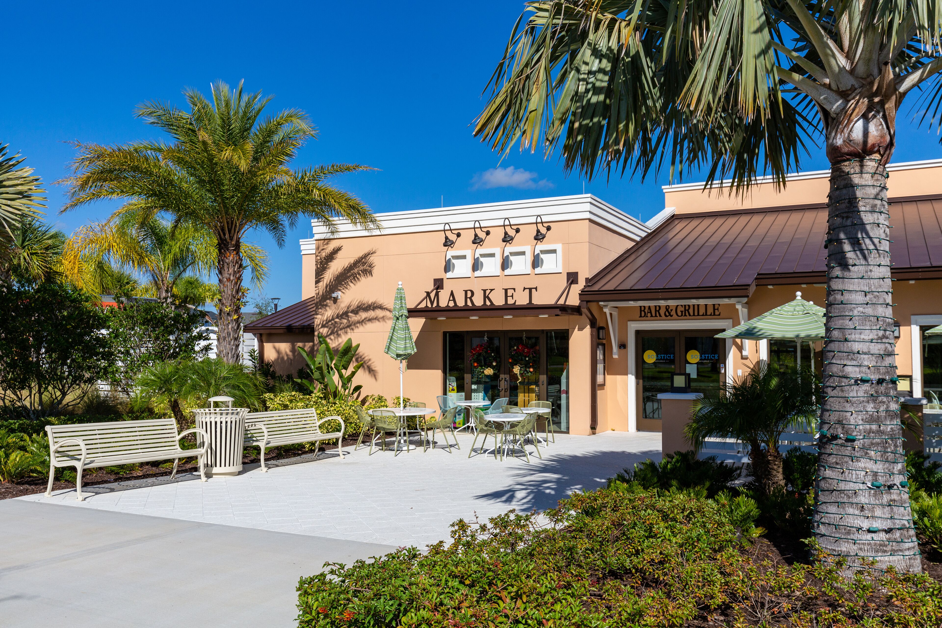 A building with a 'MARKET' sign, outdoor seating, and palm trees.