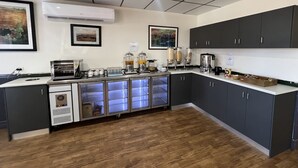 Una cocina moderna con una estación de café integrada, un refrigerador y un microondas.