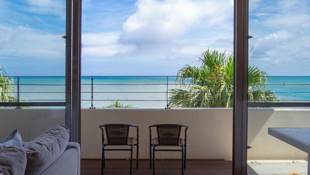 A balcony with a view of the ocean, two wicker chairs, a sofa, and a small table. - BLUE POINT OKINAWA (Yomitan)