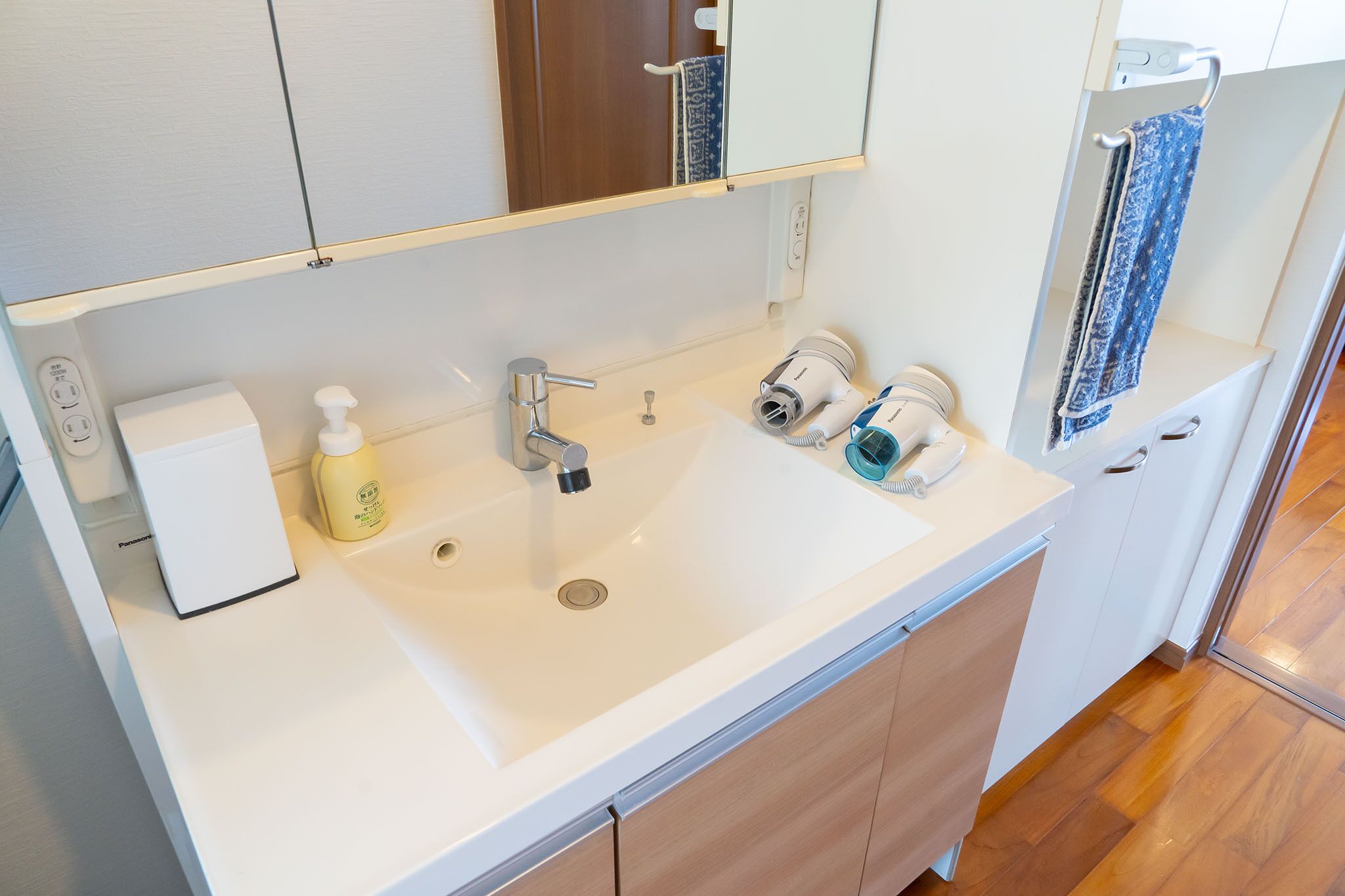 A modern bathroom with a white sink, a mirror, and a towel rack.