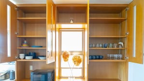 A kitchen with wooden cabinets, a microwave, and a vase with flowers. - BLUE POINT OKINAWA (Yomitan)
