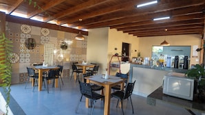 Un restaurante con mesas y sillas de madera, una barra con máquinas de café y baldosas decorativas en las paredes.
