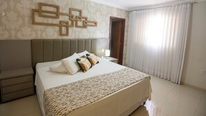Habitación de hotel ordenada con una cama grande, una mesita de noche y un espejo.
