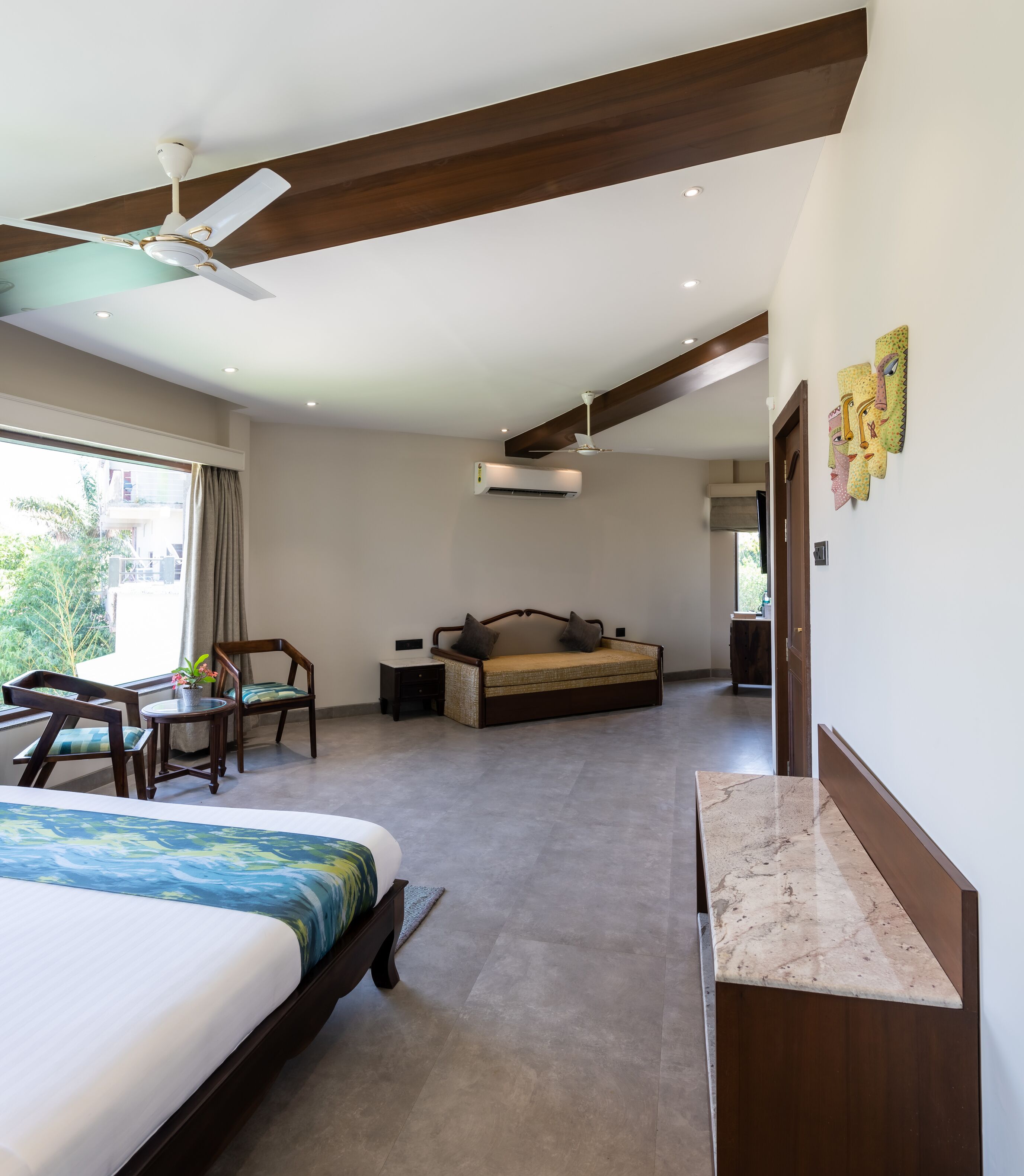 A hotel room with a bed, a desk, a chair, a sofa, and a bathroom.