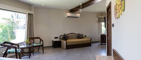 A hotel room with a bed, a desk, a chair, a sofa, and a bathroom.