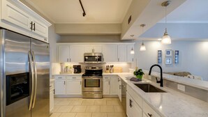 A modern kitchen with stainless steel appliances, white cabinetry, and pendant lighting. - Sun-Soaked & Heated Pool Home - Minutes to Siesta Key (Sarasota)