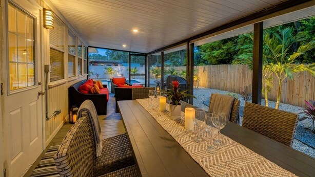 A covered patio area with a dining table set for two, surrounded by wicker furniture and candles. - Sun-Soaked & Heated Pool Home - Minutes to Siesta Key (Sarasota)