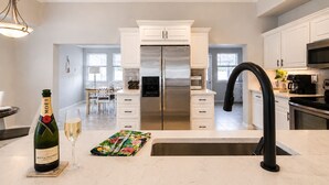 A modern kitchen with white cabinetry, stainless steel appliances, and a black faucet. - Sun-Soaked & Heated Pool Home - Minutes to Siesta Key (Sarasota)