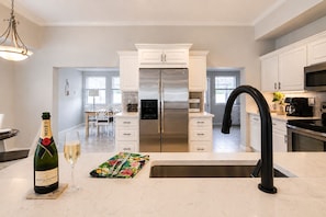 A modern kitchen with white cabinetry, stainless steel appliances, and a black faucet.