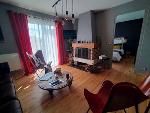 Cozy living room with a fireplace, comfortable seating area, and large window.