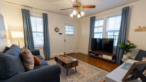 A living room with a sofa, coffee table, TV, and a ceiling fan. - Historic Revival King Bed Midtown Memphis 68 (Memphis)