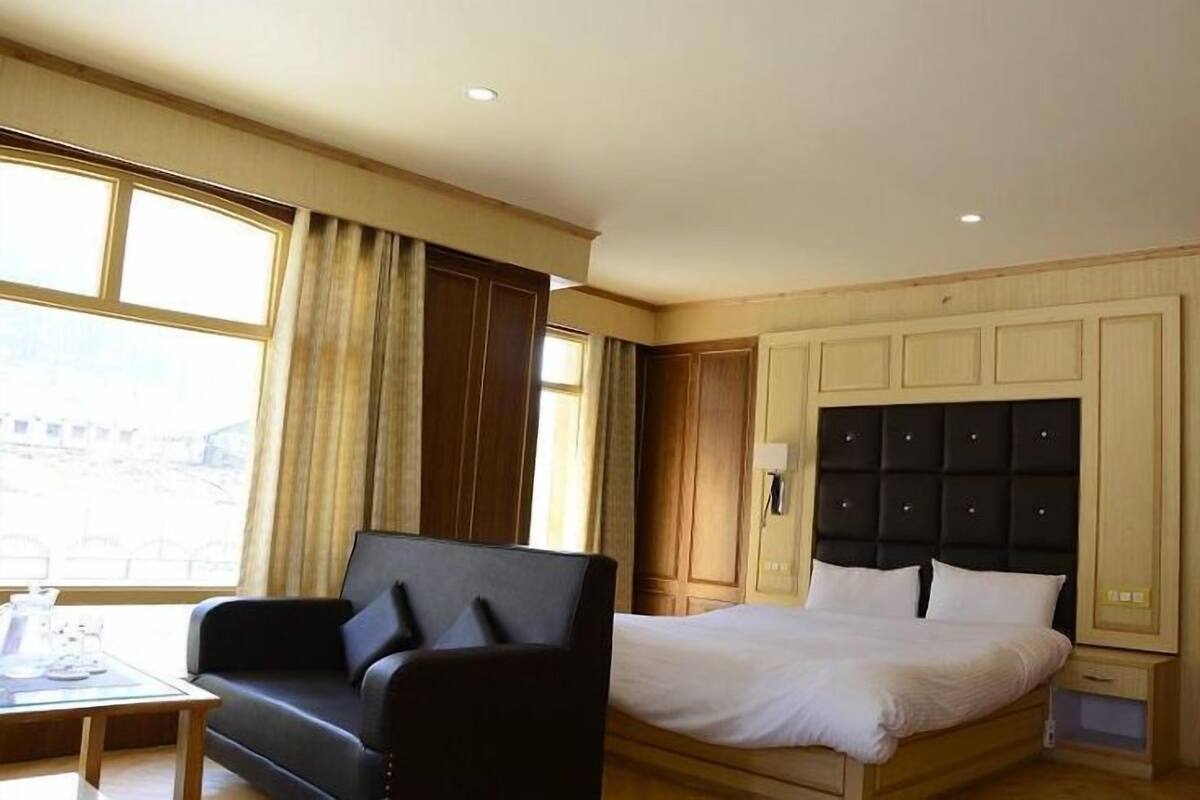 A hotel room with a bed, a desk, and a chair.