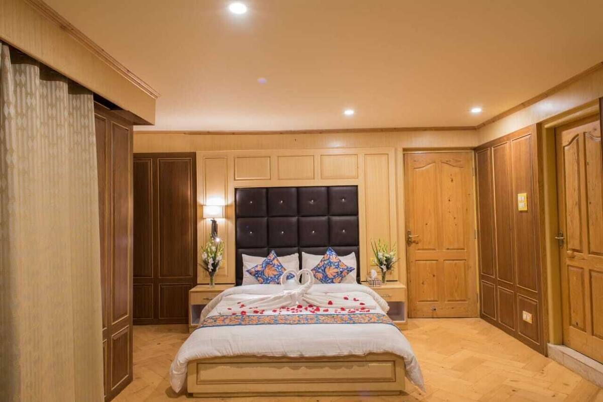 A bedroom with a large bed, wooden paneling, and a dark headboard.