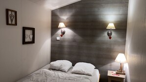 A bedroom with a wooden headboard, two bedside lamps, a bedside table with a lamp, and heart-shaped wall decorations.