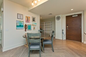 Un comedor con una mesa redonda y cuatro sillas, una puerta de madera y una pared decorada con cuadros.