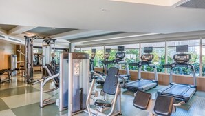 Et fitnesscenter med forskellig træningsudstyr, herunder løbebånd, styrkemaskiner og en romaskine.