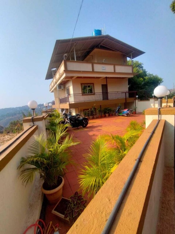 Ein zweistöckiges Gebäude mit Balkon, Blumentöpfen und einem abgestellten Motorrad.