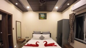 A hotel room with a bed, a ceiling fan, a painting, a wardrobe, and a window with curtains. - Royal Palace Panchgani (Mahabaleshwar)