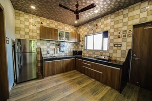 Eine Küche mit Holzausstattung, einem Edelstahlkühlschrank, einem Gasherd und einem Deckenventilator.