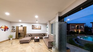 Ein modernes Wohnzimmer mit einem Ecksofa, einem Couchtisch und einer Glastür zum Poolbereich.